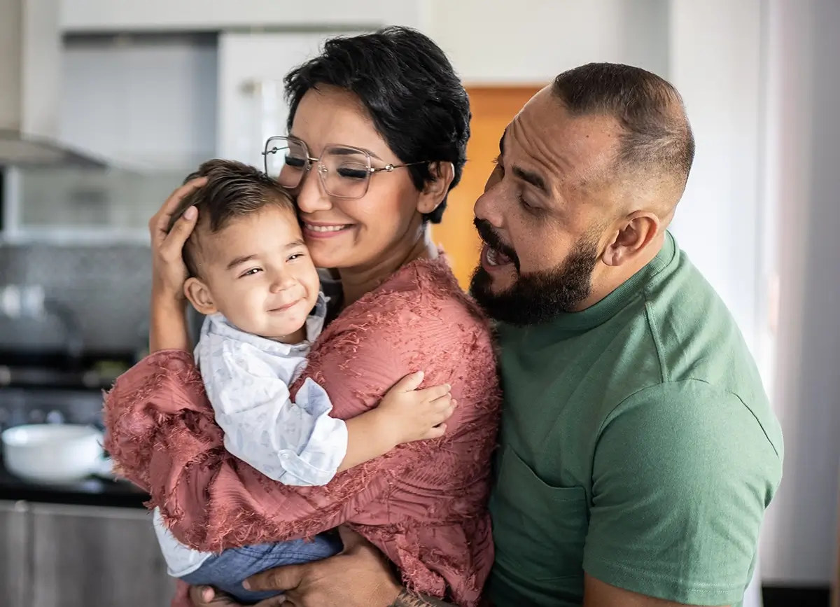A young family in the kitchen hugging and smiling
