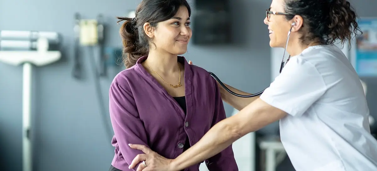 Primary care provider listening to patient's heart beat