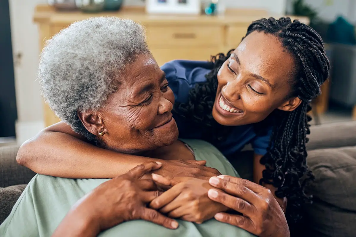 A woman wrapping her arms around an elderly woman